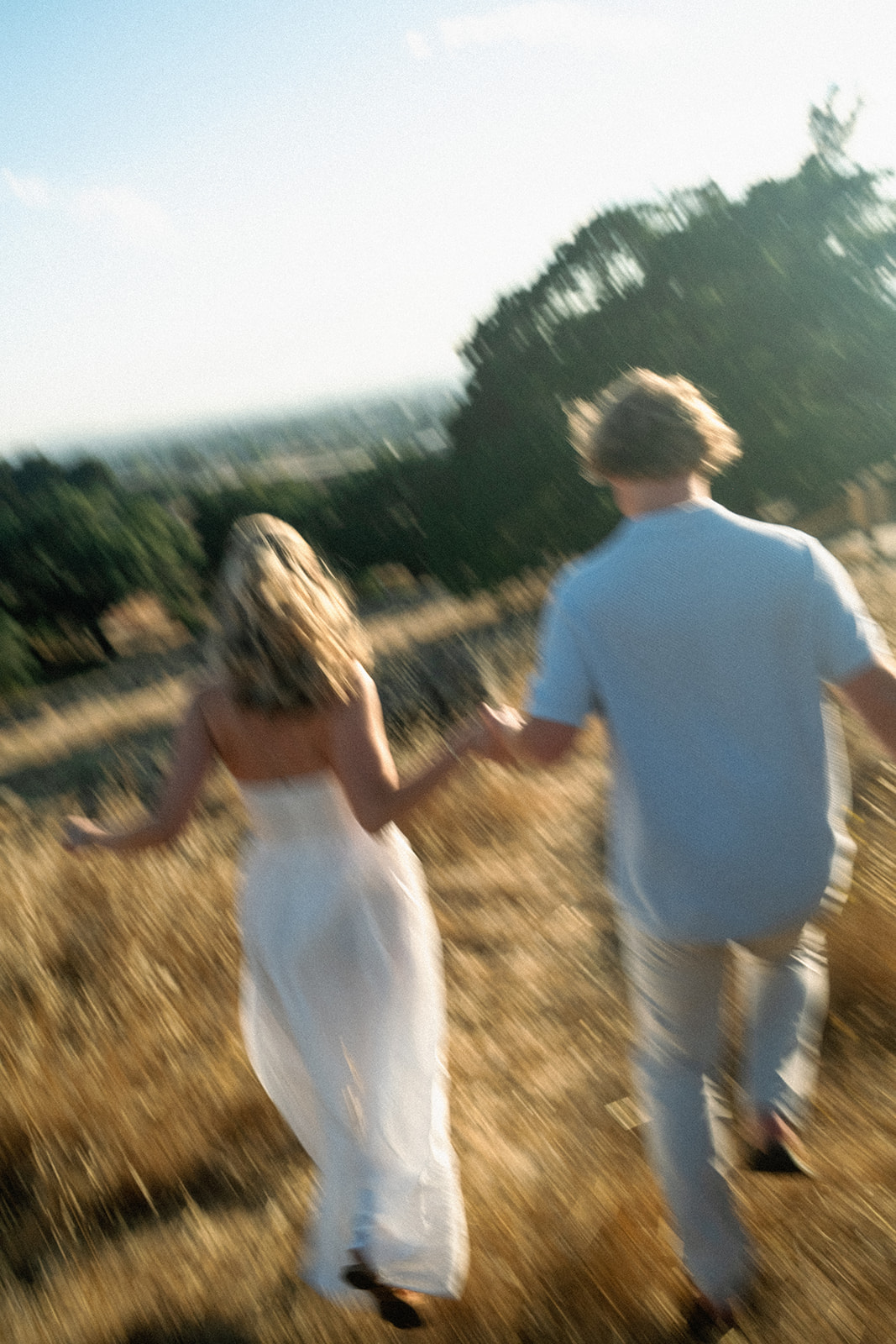 Chloe and Cal running hand in hand through a golden field